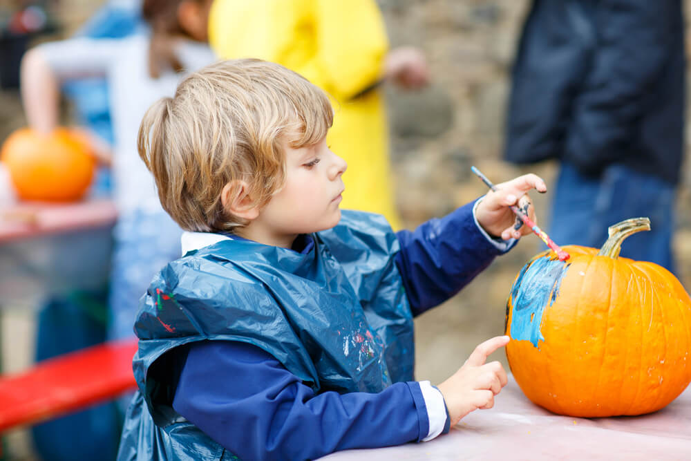 A child painting a pumpkin at one of the fall festivals in Midcoast Maine.