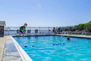 A kid jumping into a pool at a Boothbay Harbor area resort close to incredible dining options.